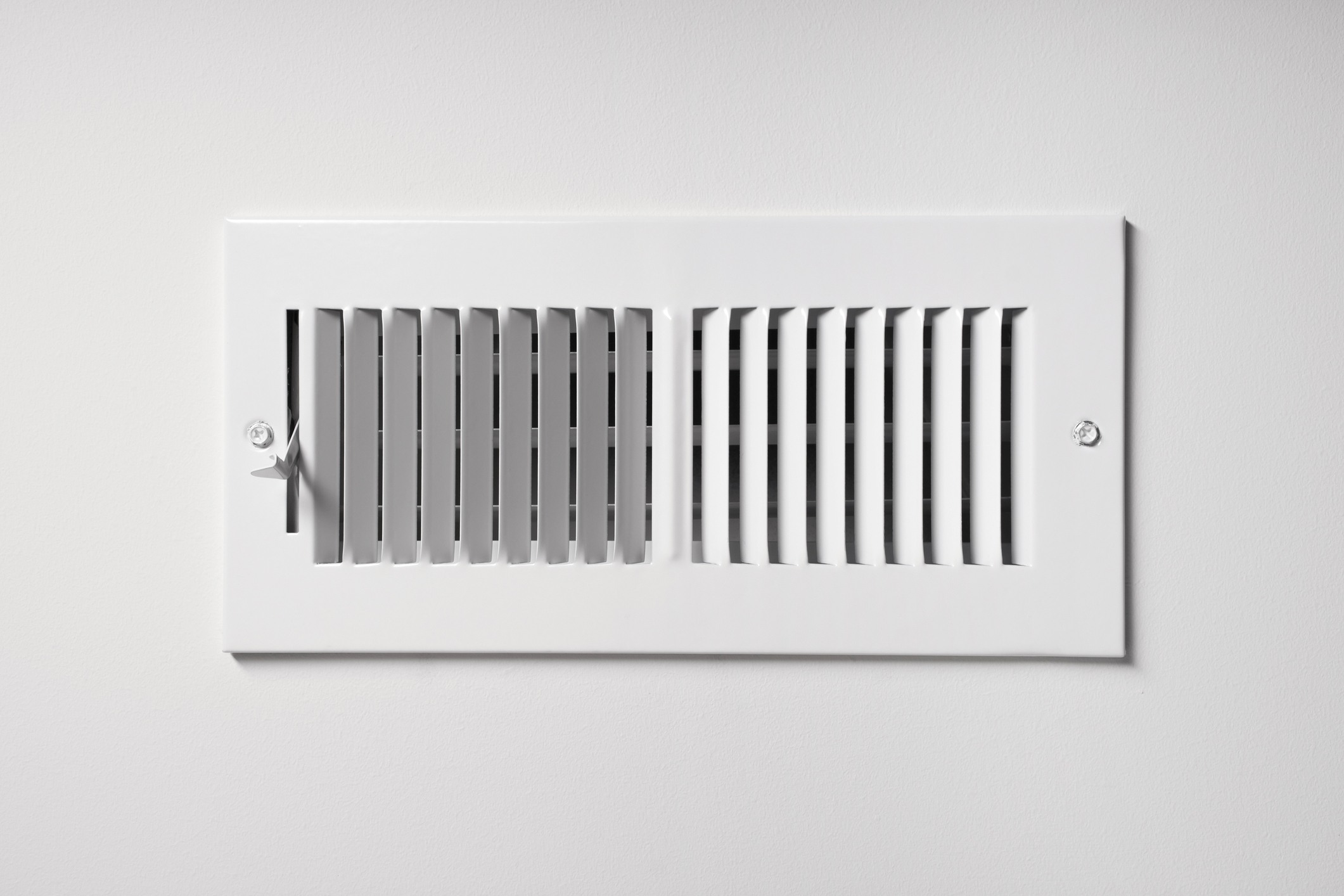 Air vent cover on a white wall, illustrating HVAC air circulation system related to heat pump maintenance and indoor climate control.
