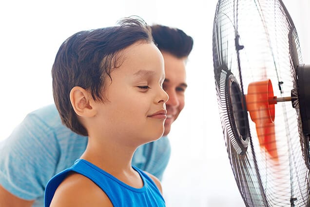 Little boy cooling off in front of a fan