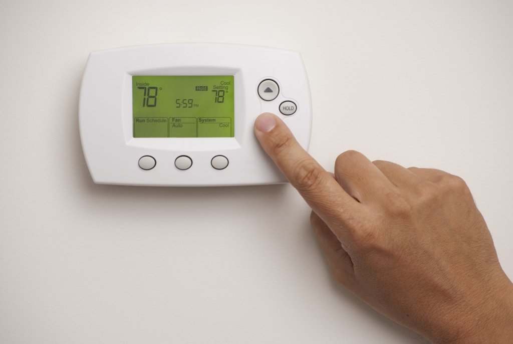 finger pressing down button on thermostat with temperature set at 78