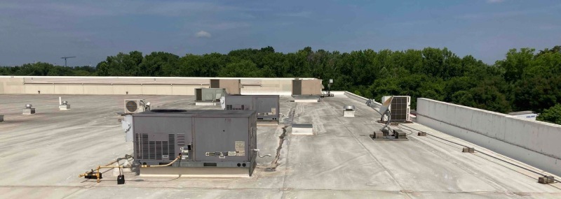 hvac units on a commercial roof with trees in the background